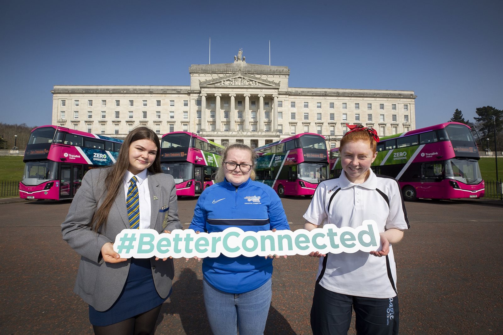 Clare, Lauren and Becky at the Translink Zero Emission buses at Stormont holding the Better Connected sign